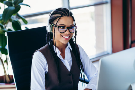 Professional young woman wearing headset working in a modern office interior, focused on corporate...
