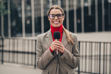 Professional businesswoman outdoors holding a microphone in a stylish outfit, conveying confidence and professionalismの写真素材