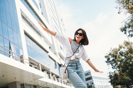 Cheerful young woman enjoys a sunny day outdoors in stylish casual attireの写真素材