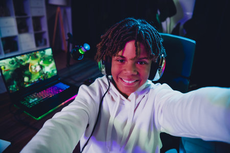 Energetic young gamer streaming from home, showcasing gaming skills with a laptop, headset, and neon vibesの写真素材