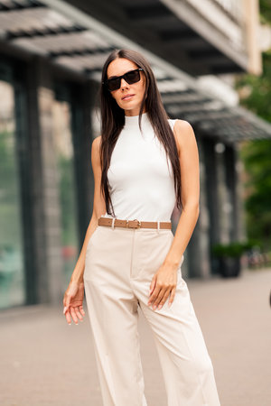 Confident businesswoman in elegant attire walking along a modern city street, embracing a chic and stylish lifestyleの写真素材