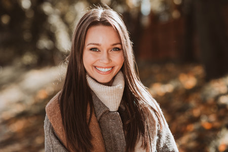 Portrait of a young woman in an autumn setting, showcasing her elegant style and gorgeous appearance under natural sunlight.の写真素材