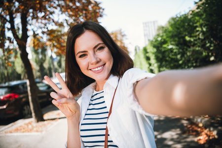 Young woman smiling in natural light on a sunny day, wearing stylish casual shirt, enjoying leisure outdoorsの写真素材