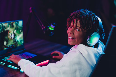 Teenage gamer with headset streaming online from home using advanced gaming setup under vibrant neon lightingの写真素材