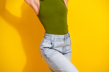 Stylish young woman in casual modern fashion outfit posing against yellow background with vibrant colors and energyの写真素材