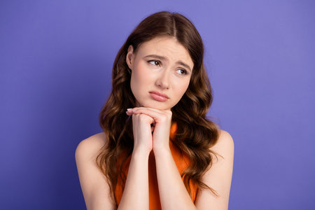 Adorable and thoughtful, a young woman looking charming in casual fashion against a purple...