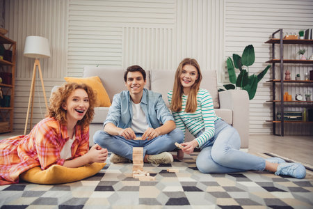 Cheerful friends spending time together at home playing a game and enjoying a relaxing and fun...