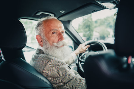 Confident elder gentleman driving a modern car in an urban setting, portraying elegance and professionalism with stylish demeanorの写真素材