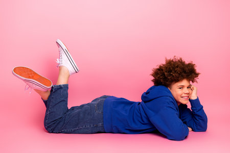 Charming young boy smiling in vibrant clothing against a pink background, showcasing a cheerful and stylish demeanor.の写真素材