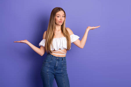 Young woman in a stylish casual outfit makes a gesture expressing curiosity against a vibrant purple backgroundの写真素材