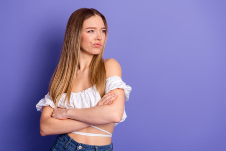 Attractive young woman wearing a white top posing with attitude on a violet background, showing casual and trendy styleの写真素材