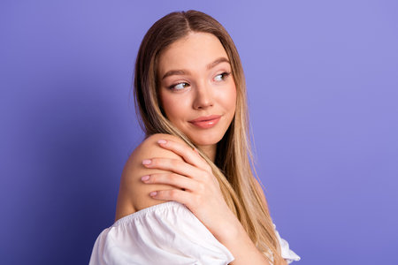 Beautiful young woman posing with a charming smile on violet background, showcasing casual fashion and eleganceの写真素材