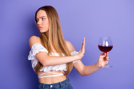 Young woman on purple background refusing wine with a gesture, wearing casual trendy clothes, concept of choice and self-expressionの写真素材