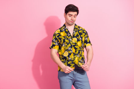 Young man wearing a tropical print shirt posing playfully against a vibrant pink background conveying vacationの写真素材