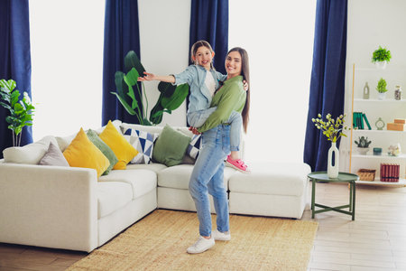 Young mother and daughter bonding together in a stylish modern home interior with bright accents and cozy furnitureの写真素材