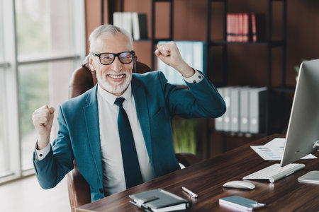Businessman Celebrating Success in Professional Office with Confident Smile and Hands Raised for...