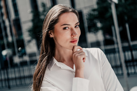 Charming young businesswoman in urban setting expressing professionalism and elegance wearing formal attire during daylightの写真素材
