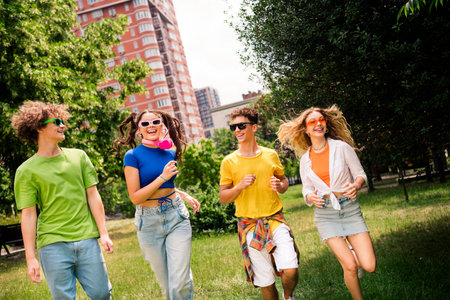 Group of cheerful friends enjoying a sunny day together outdoors surrounded by greenery and vibrant...