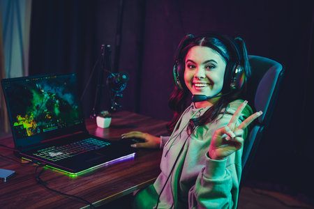 Young female gamer streaming live from home with a headset, engaging with online community on her...