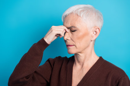 Mature Woman with Short Grey Hair in Thoughtful Pose Against Blue Background
