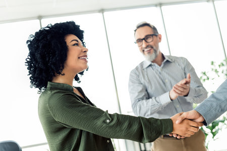 Business professionals collaborating at a corporate office, with executives shaking hands and fostering teamworkの写真素材