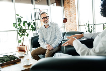 Professional meeting between diverse business professionals in a well-decorated office focusing on collaborative discussionの写真素材