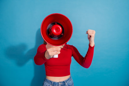 Young woman holding a red megaphone, wearing casual red top, blue jeans, vibrant background,...