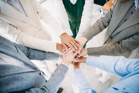 Closeup of diverse business professionals stacking hands in unity, symbolizing teamwork, dedication,...