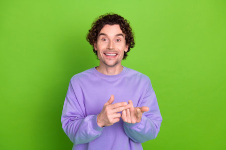 Young stylish man in purple pullover gesturing with excitement against a bright green background in...