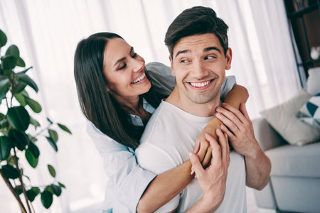 Young couple sharing joy and bonding in a cozy living room with natural lighting and modern interior...
