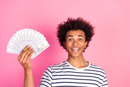 Young Man Holding Banknotes Enthusiastically Against a Pink Background Representing Wealth and...