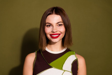 Portrait of a charming woman with red lipstick, posing against a khaki background, showcasing her...