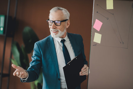 Senior businessman presenting strategy with clipboard during a meeting in office space and...