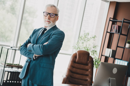 Confident senior businessman in formalwear standing in modern office workspace showcasing...