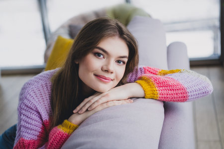 Charming Young woman relaxing indoors with a colorful knitted sweater, enjoying leisure time at home