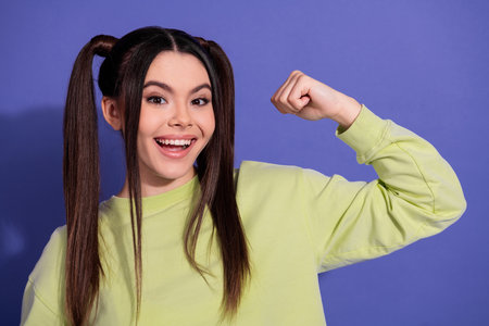 Smiling young woman in casual attire gesturing confidently on a purple background