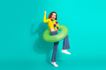 Positive young woman enjoying leisure time with vibrant accessories against a teal turquoise...