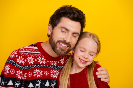 Father and Daughter Sharing a Joyful Holiday Moment Against a Bright Yellow Backgroundの写真素材