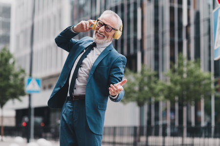 Successful mature businessman enjoying music outdoors in urban setting showcasing vitality and...