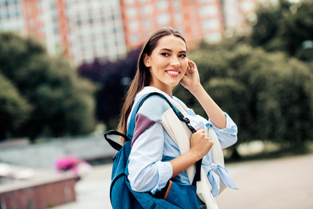 Lovely woman enjoying outdoor leisure with a backpack, expressing happiness and style in a casual...