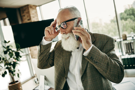 Elegant Elderly Man in Formal Attire Speaking on Phone at Modern Office Space with Cityscape View in...