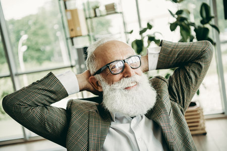 Elderly businessman relaxing, leaning back in office, confident mature entrepreneur in stylish...