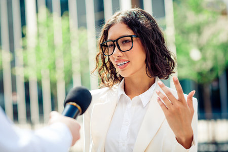 Confident businesswoman in smart attire gives an outdoor interview in a modern urban setting on a...