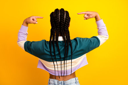 Young woman with braided hair pointing to herself against colorful yellow background showcasing...