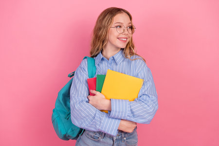 Smiling young woman student holding colorful notebooks in casual style on pink background...