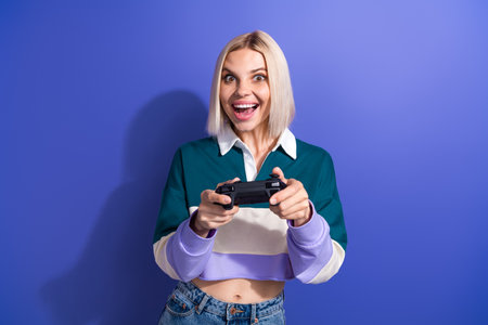 Young cheerful woman enjoying video gaming experience with a controller on a vibrant purple...