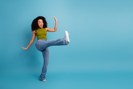 Energetic young woman in casual attire having fun against a bright blue backgroundの写真素材