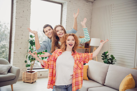 Funny young friends in a cozy living room enjoying a joyful moment together under natural daylight conditions.の写真素材