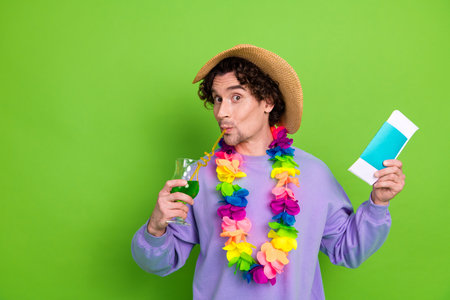 Young man enjoying tropical drink and vibrant decorations on a cheerful green background