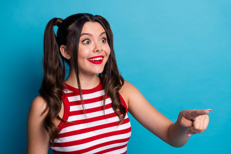 Cheerful young woman with twin ponytails pointing excitedly in a dynamic pose, emphasizing joy...